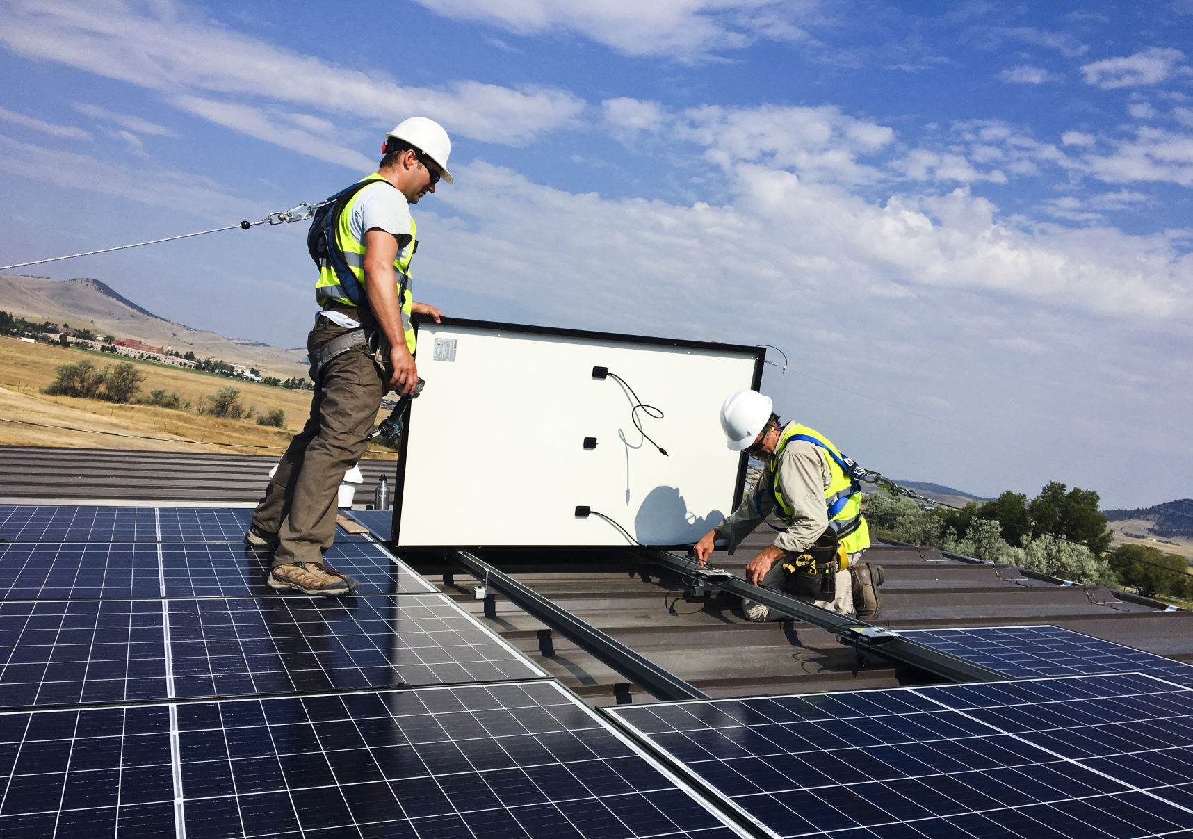 Crews members of Solar Montana install a solar panel array